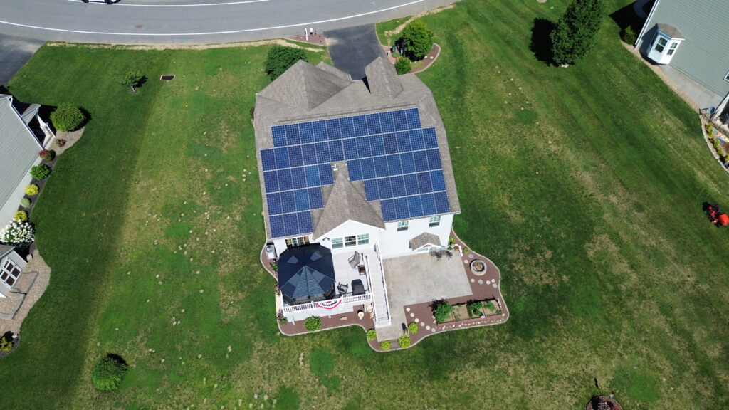 A drone shot shows solar panels across the entire back half of a roof for a real estate listing. 